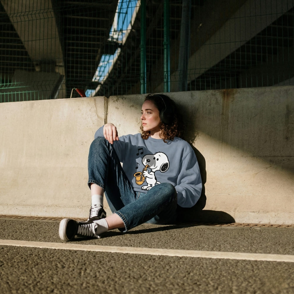 Person wearing a blue sweatshirt with a graphic design, sitting on a concrete surface.