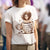 Person wearing a white t-shirt with a graphic design of a person holding a coffee cup and text.
