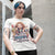 Person wearing a t-shirt with a colorful graphic and text, standing outdoors.