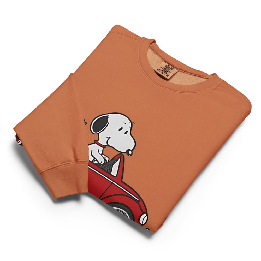 Folded orange sweatshirt with a cartoon dog design on a white background
