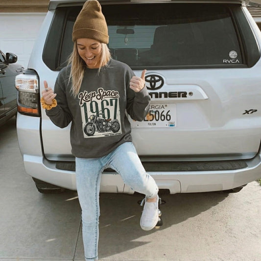 Person wearing a gray sweatshirt with a graphic design in front of a Toyota vehicle