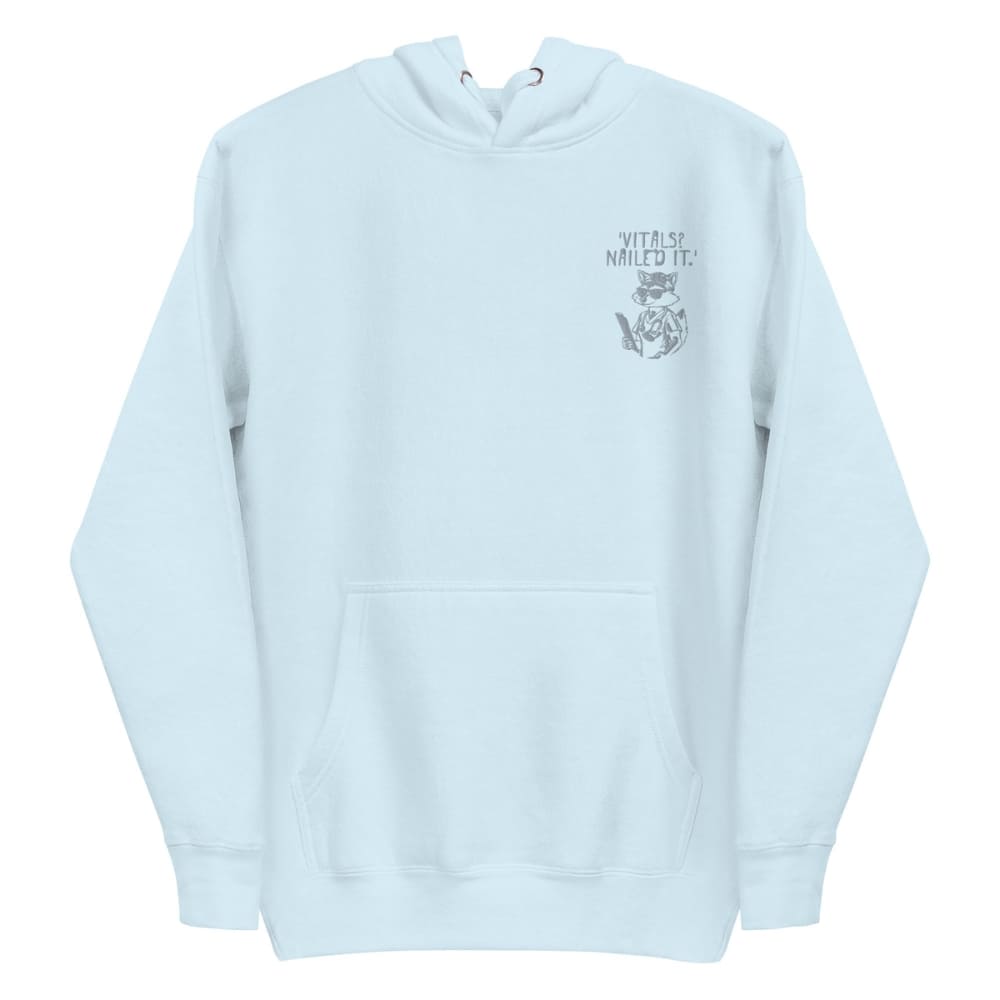 Raccoon nurse graphic wearing scrubs and sunglasses holding a clipboard under the quote “Vitals? Nailed It.” – printed on a black Cotton Heritage hoodie