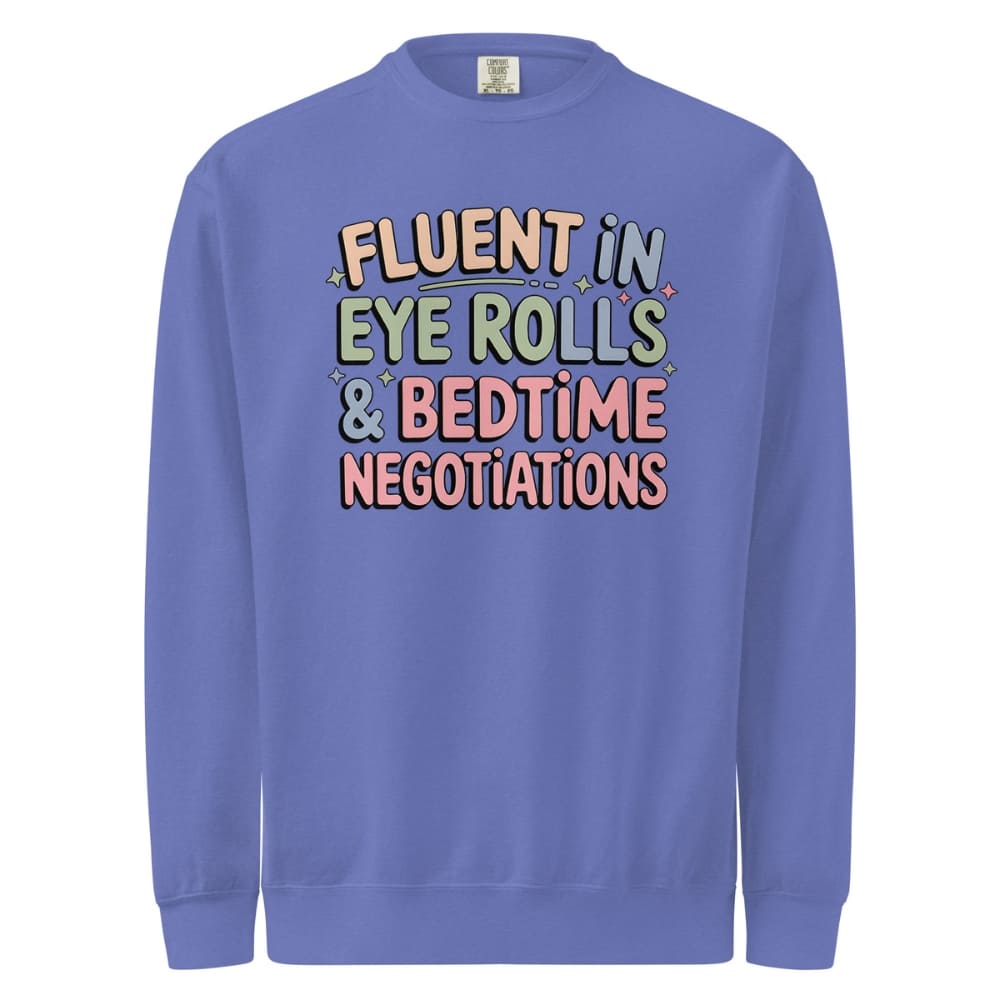 Blue sweatshirt with colorful text 'Fluent in Eye Rolls & Bedtime Negotiations' on a white background
