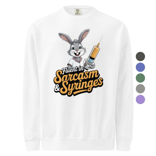 White long-sleeve shirt with cartoon character and text 'Fluent in Sarcasm & Syringes' on a white background.
