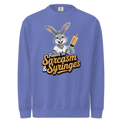 Blue sweatshirt with cartoon character holding a syringe and text 'Fluent in Sarcasm & Syringes' on a white background