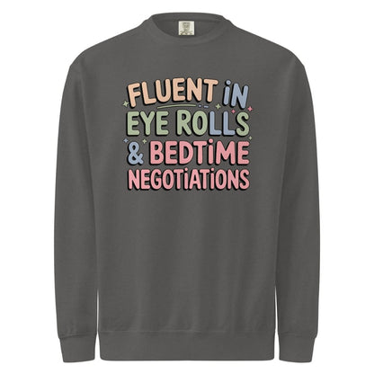 Pastel-colored quote sweatshirt design that reads “Fluent in Eye Rolls & Bedtime Negotiations” in playful fonts on black background.