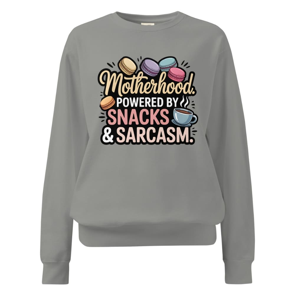 Sweatshirt design with text “Motherhood. Powered by Snacks & Sarcasm.” featuring colorful macarons and a steaming coffee cup on vintage-washed cotton fleece.