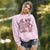 Woman wearing a pink sweatshirt with a graphic design outdoors