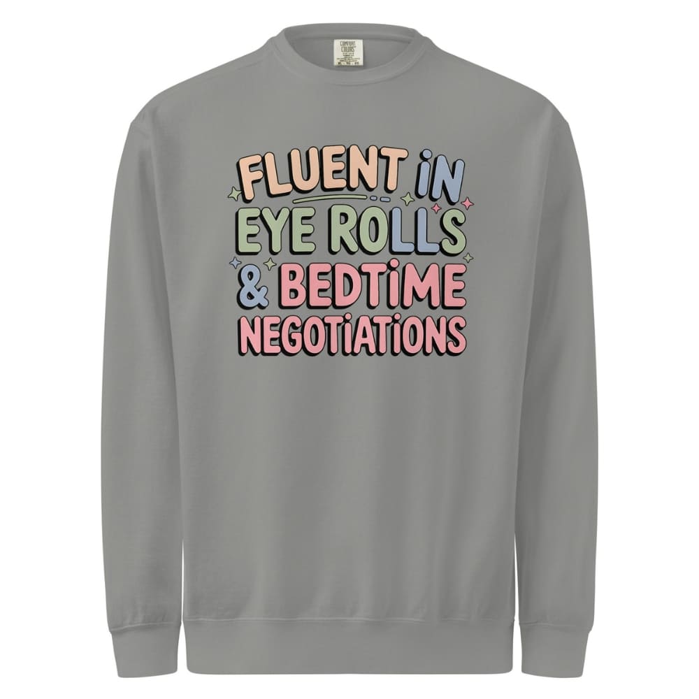 Gray sweatshirt with colorful text 'FLUENT IN EYE ROLLS & BEDTIME NEGOTIATIONS' on a white background