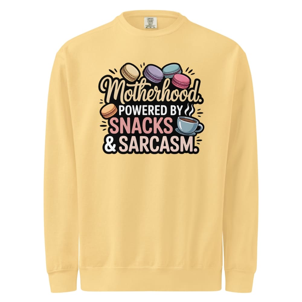 Sweatshirt design with text “Motherhood. Powered by Snacks & Sarcasm.” featuring colorful macarons and a steaming coffee cup on vintage-washed cotton fleece.