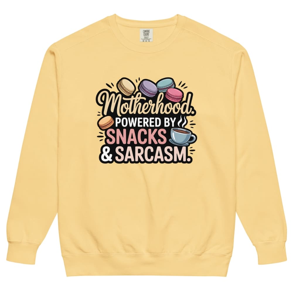 Sweatshirt design with text “Motherhood. Powered by Snacks & Sarcasm.” featuring colorful macarons and a steaming coffee cup on vintage-washed cotton fleece.