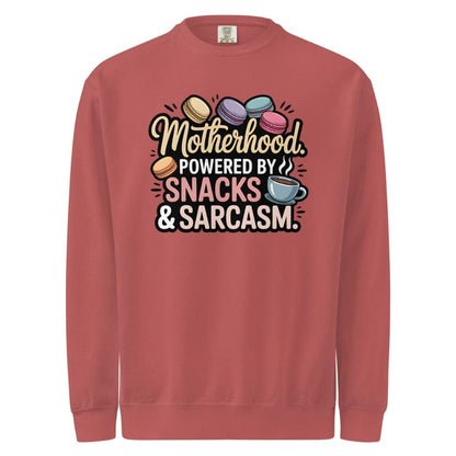Sweatshirt design with text “Motherhood. Powered by Snacks & Sarcasm.” featuring colorful macarons and a steaming coffee cup on vintage-washed cotton fleece.
