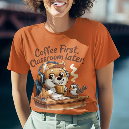 Person wearing an orange t-shirt with a cartoon fox and bird design and text 'Coffee First, Classroom later.'