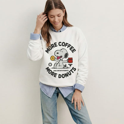 Woman wearing a white sweatshirt with a cartoon character and text, standing against a plain background.