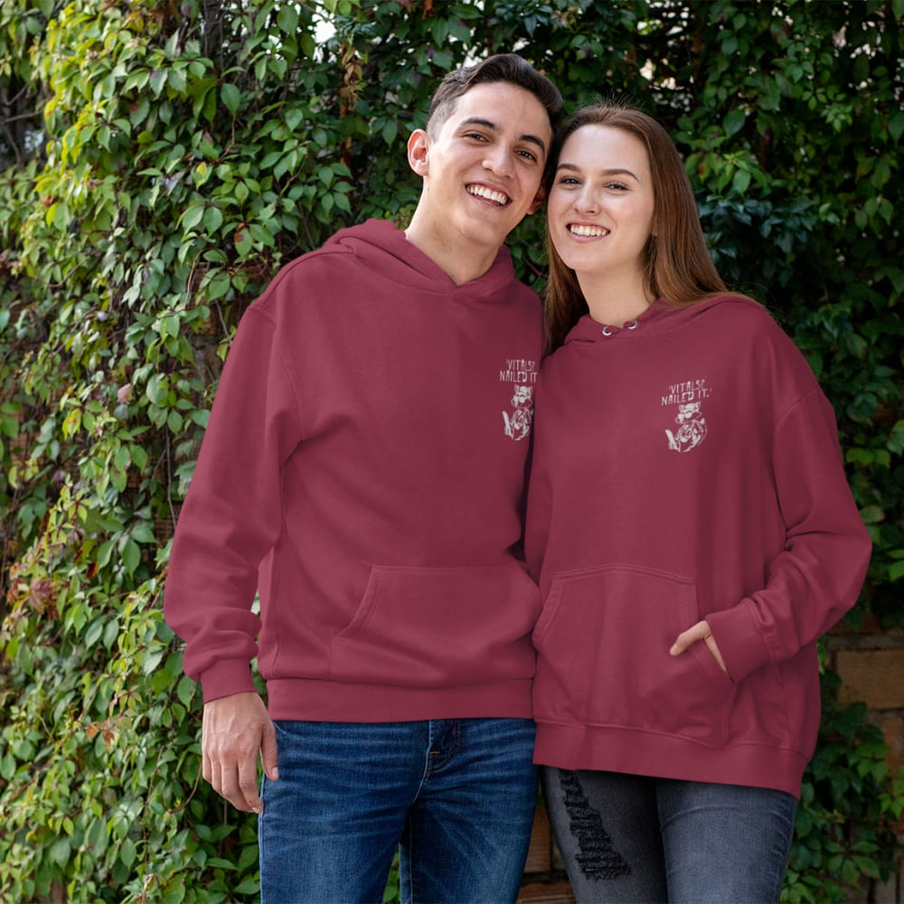 Raccoon nurse graphic wearing scrubs and sunglasses holding a clipboard under the quote “Vitals? Nailed It.” – printed on a black Cotton Heritage hoodie