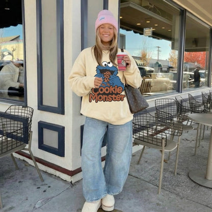 Person wearing a Cookie Monster sweatshirt standing outside a cafe.