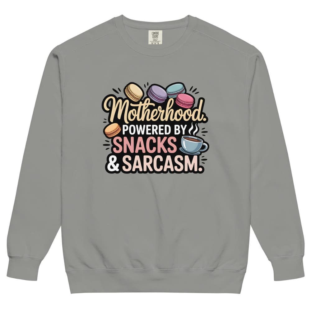 Sweatshirt design with text “Motherhood. Powered by Snacks & Sarcasm.” featuring colorful macarons and a steaming coffee cup on vintage-washed cotton fleece.