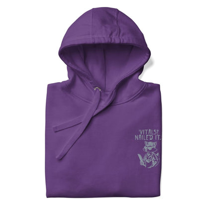 Raccoon nurse graphic wearing scrubs and sunglasses holding a clipboard under the quote “Vitals? Nailed It.” – printed on a black Cotton Heritage hoodie