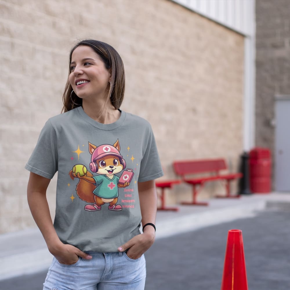 Cute squirrel nurse cartoon in scrubs, pink cap, and headset holding a softball and medical kit with the phrase “Saving Lives Between Innings” — printed on a heavyweight cotton t-shirt