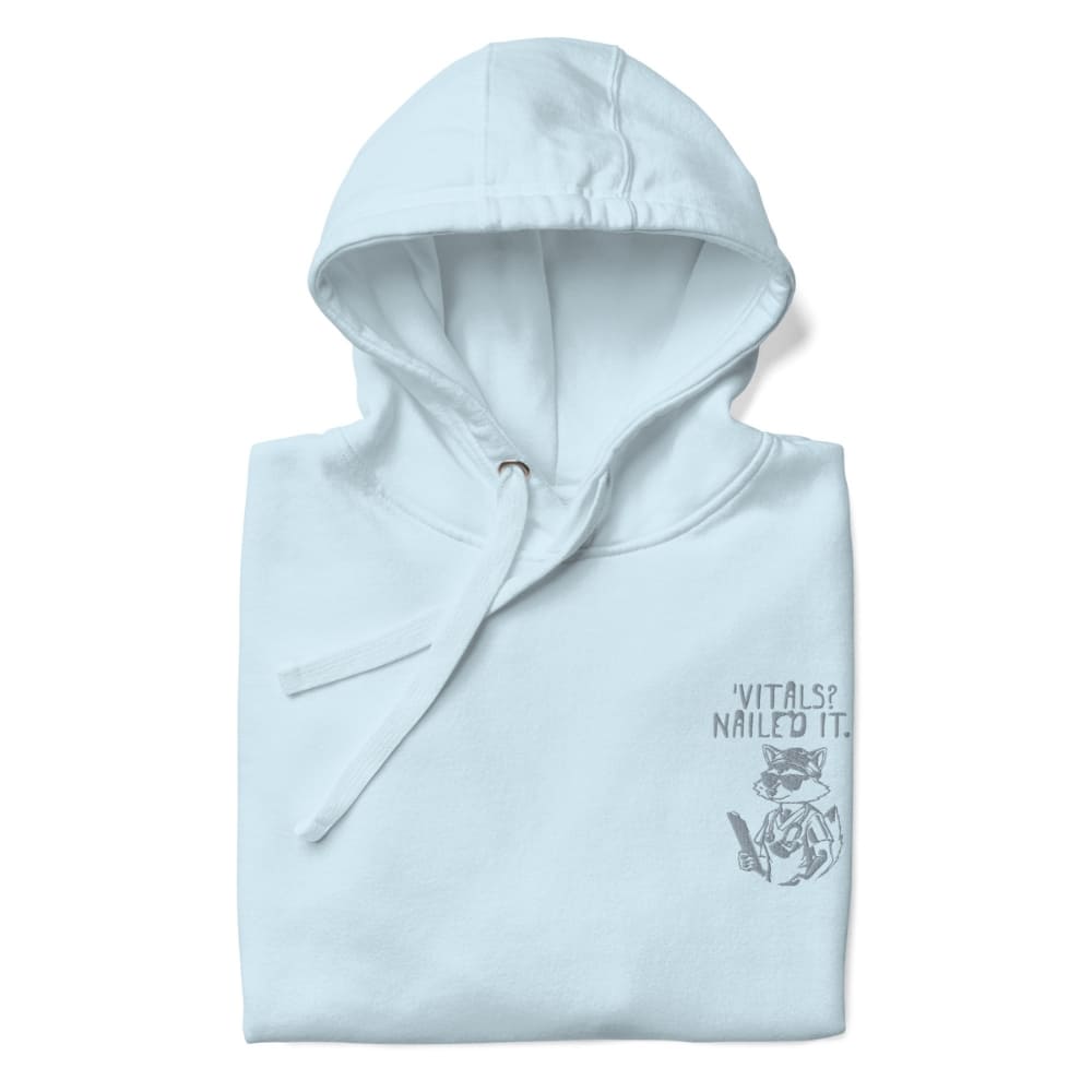Raccoon nurse graphic wearing scrubs and sunglasses holding a clipboard under the quote “Vitals? Nailed It.” – printed on a black Cotton Heritage hoodie