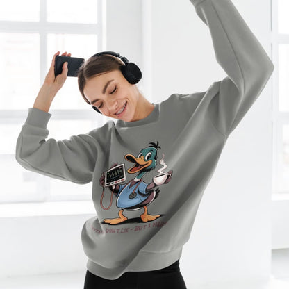 Person wearing a gray sweatshirt with a cartoon character, holding a phone and wearing headphones.