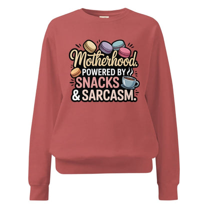 Sweatshirt design with text “Motherhood. Powered by Snacks & Sarcasm.” featuring colorful macarons and a steaming coffee cup on vintage-washed cotton fleece.