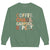 Green sweatshirt with colorful text 'COFFEE. CHAOS. CARPOOL. REPEAT.' on a white background