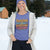 Person wearing a purple sweater with colorful text in a snowy outdoor setting