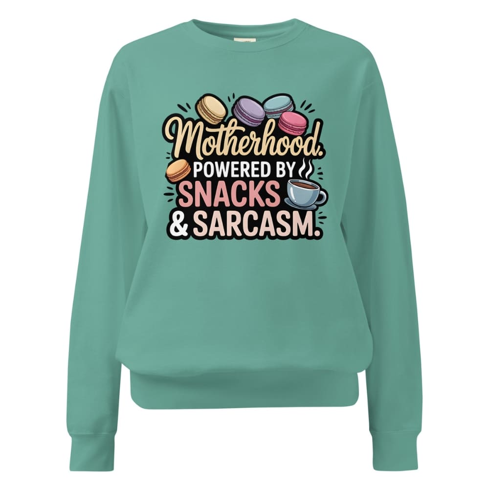 Sweatshirt design with text “Motherhood. Powered by Snacks & Sarcasm.” featuring colorful macarons and a steaming coffee cup on vintage-washed cotton fleece.