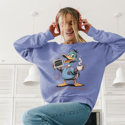 Person wearing a blue sweatshirt with a cartoon duck design, sitting indoors.