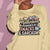 Sweatshirt design with text “Motherhood. Powered by Snacks & Sarcasm.” featuring colorful macarons and a steaming coffee cup on vintage-washed cotton fleece.