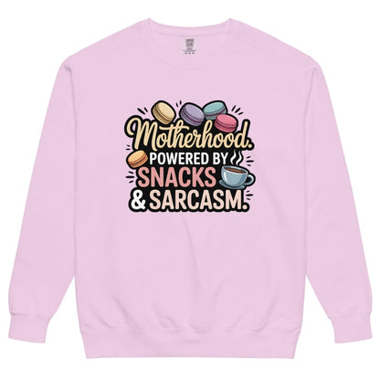 Sweatshirt design with text “Motherhood. Powered by Snacks & Sarcasm.” featuring colorful macarons and a steaming coffee cup on vintage-washed cotton fleece.