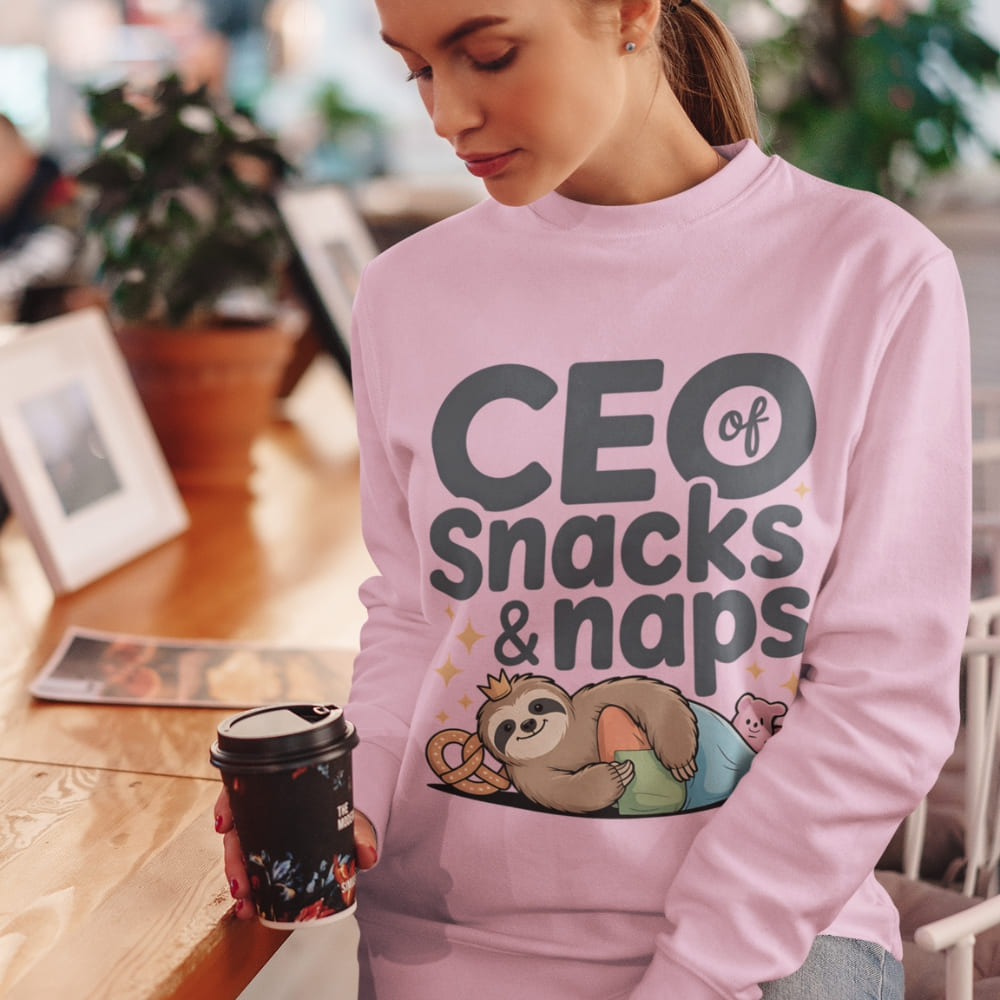 "CEO of Snacks & Naps" printed sweatshirt featuring a sloth in a crown surrounded by pretzels and plushies on vintage-washed cotton fleece