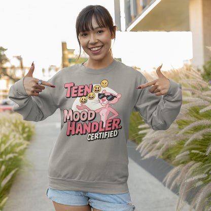 Person wearing a gray sweatshirt with a graphic design and text, standing outdoors.