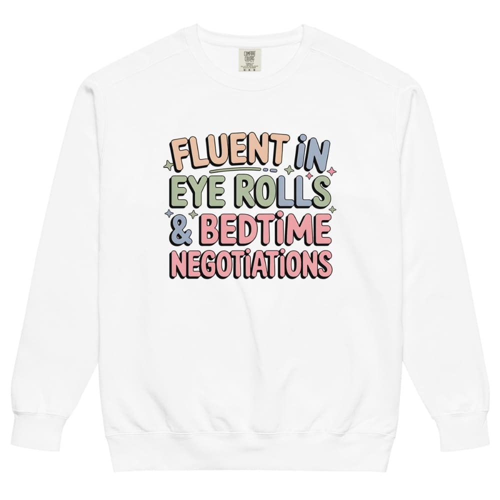 White sweatshirt with colorful text 'Fluent in Eye Rolls & Bedtime Negotiations' on a white background