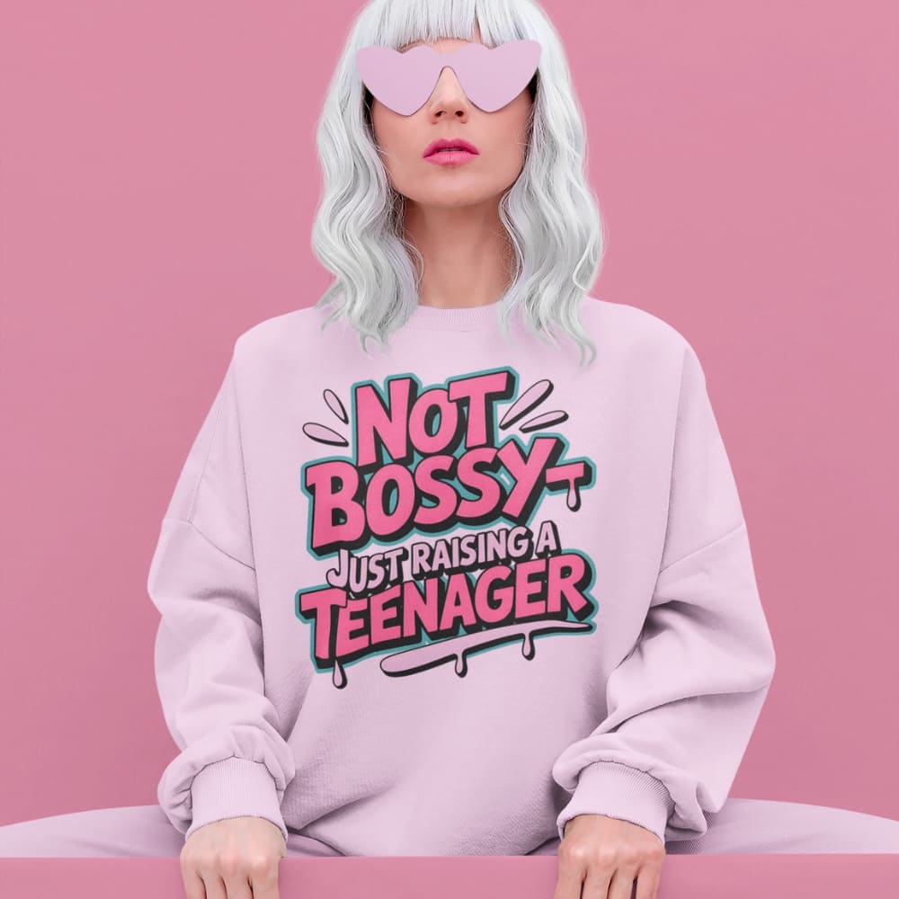 Person wearing a pink sweatshirt with 'Not Bossy Just Raising a Teenager' text on a pink background