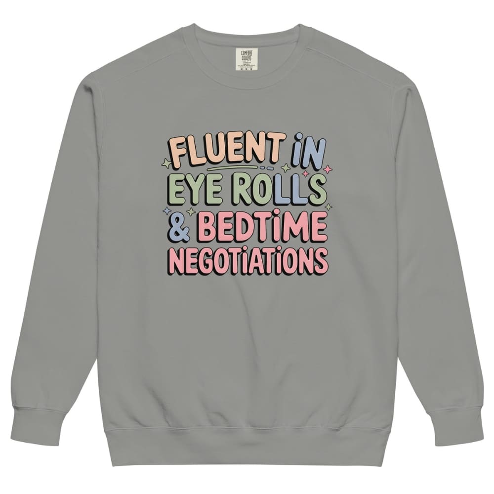 Gray sweatshirt with colorful text 'Fluent in Eye Rolls & Bedtime Negotiations' on a white background