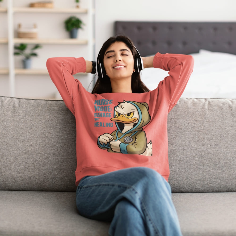 Woman wearing a pink sweatshirt with a graphic design of a duck character, sitting on a couch in a living room.