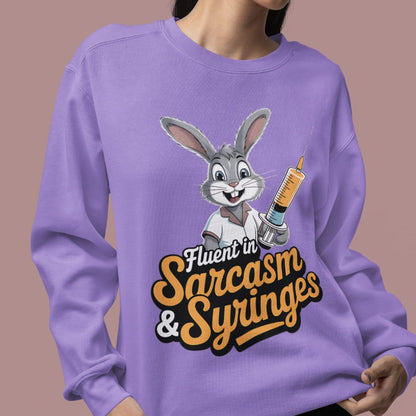Person wearing a purple sweatshirt with a cartoon character and text 'Fluent in Sarcasm & Syringes' on a brown background