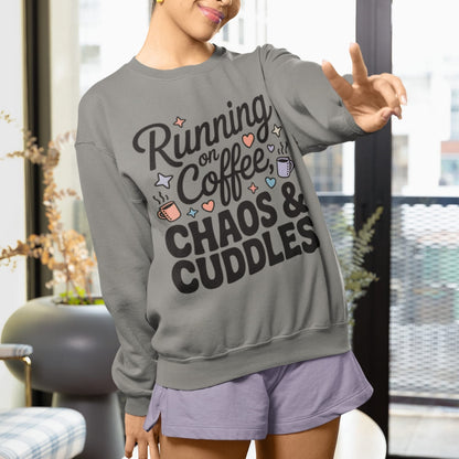 Person wearing a gray sweatshirt with text 'Running on Coffee, Chaos & Cuddles' in a home setting.
