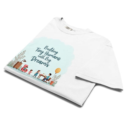 Illustrated t-shirt design with the quote "Building Tiny Humans with Big Dreams" surrounded by a family parenting scene