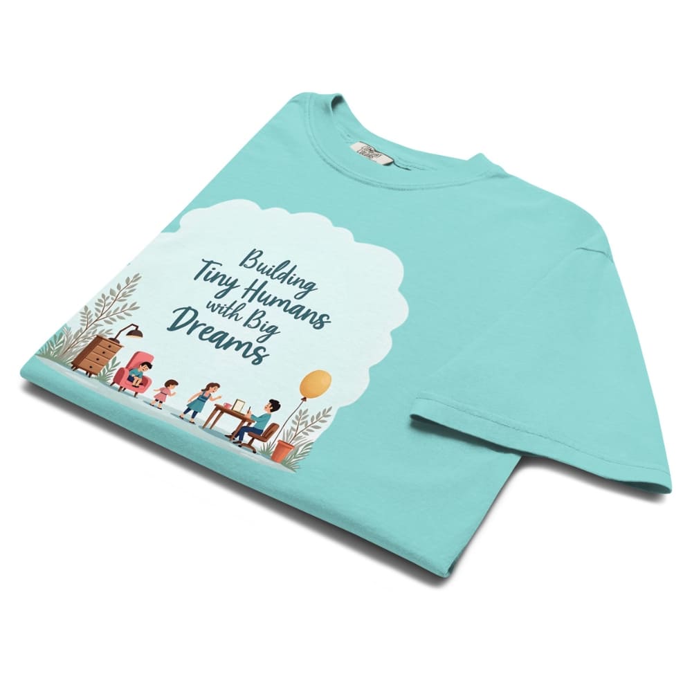 Illustrated t-shirt design with the quote "Building Tiny Humans with Big Dreams" surrounded by a family parenting scene