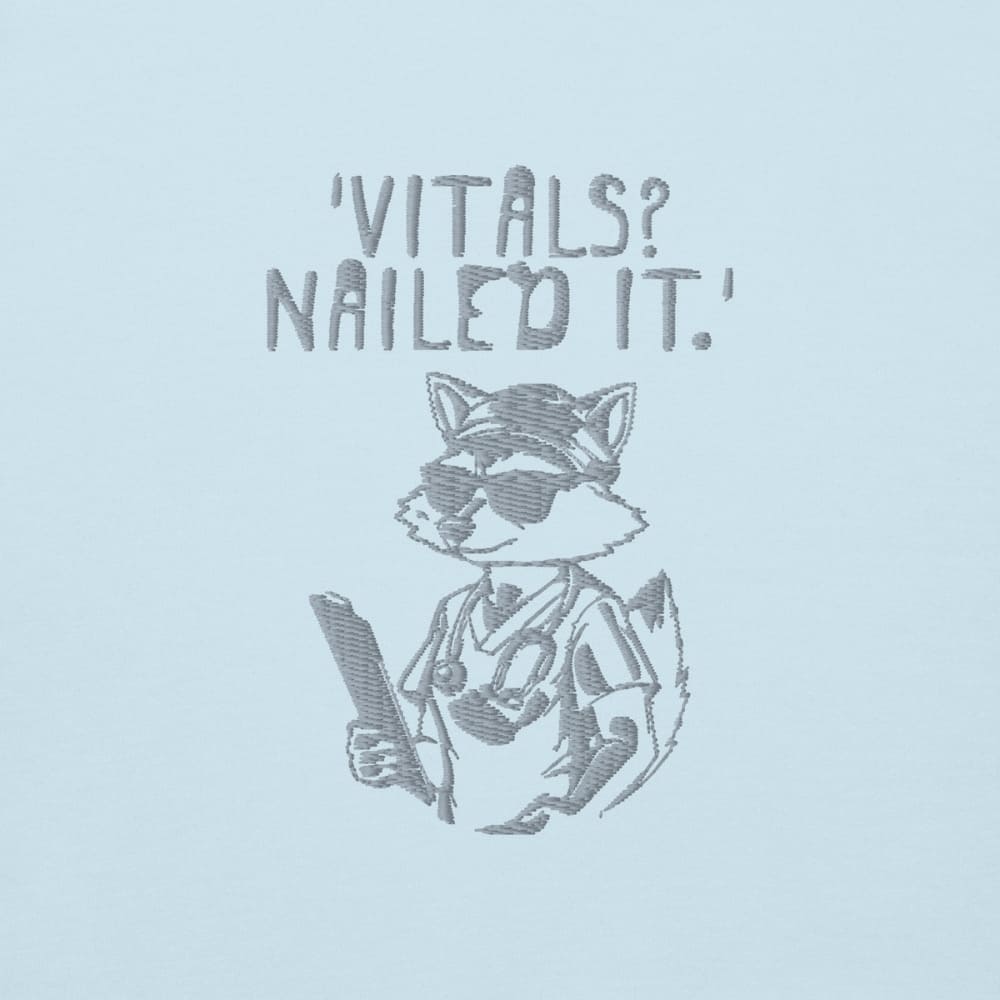 Raccoon nurse graphic wearing scrubs and sunglasses holding a clipboard under the quote “Vitals? Nailed It.” – printed on a black Cotton Heritage hoodie