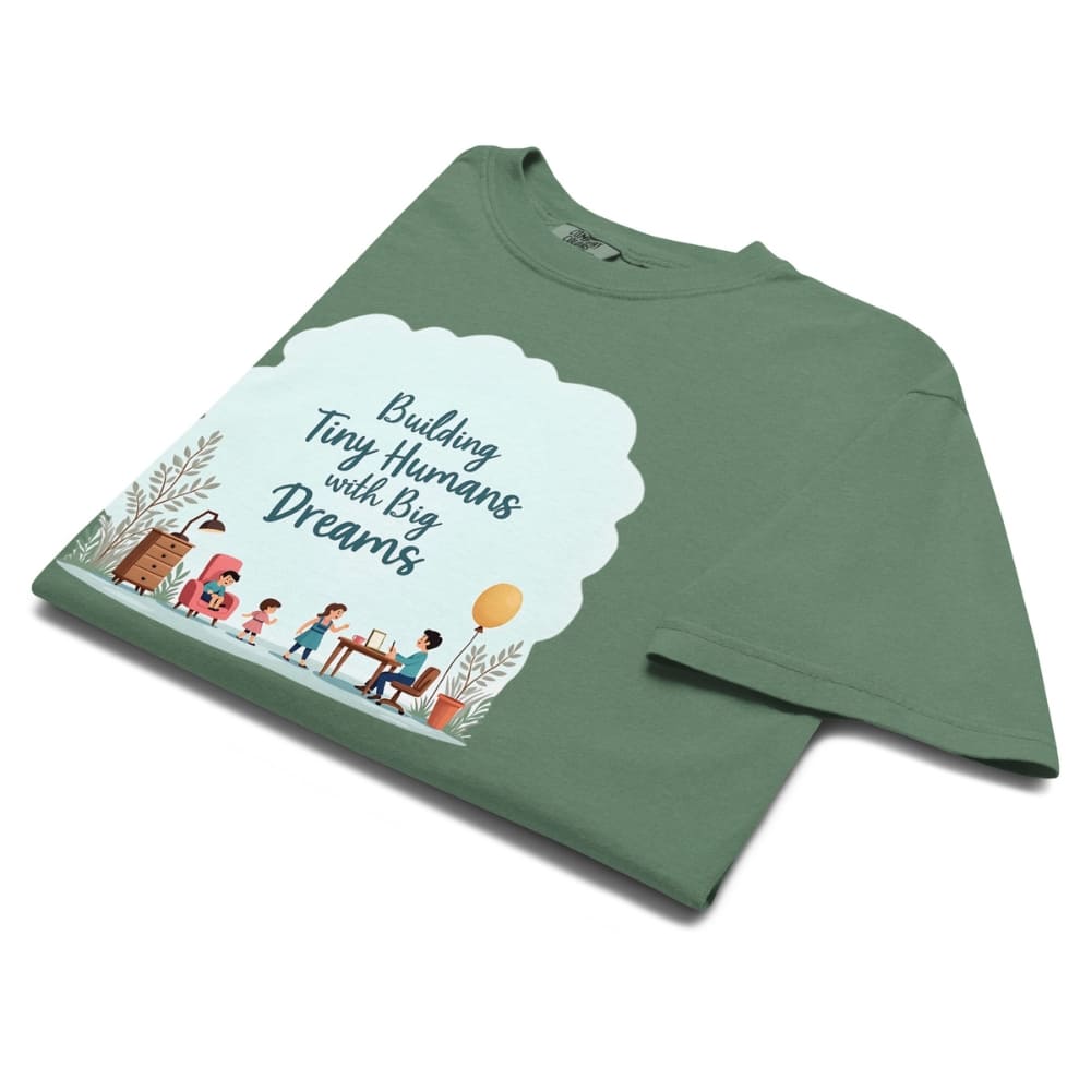 Illustrated t-shirt design with the quote "Building Tiny Humans with Big Dreams" surrounded by a family parenting scene