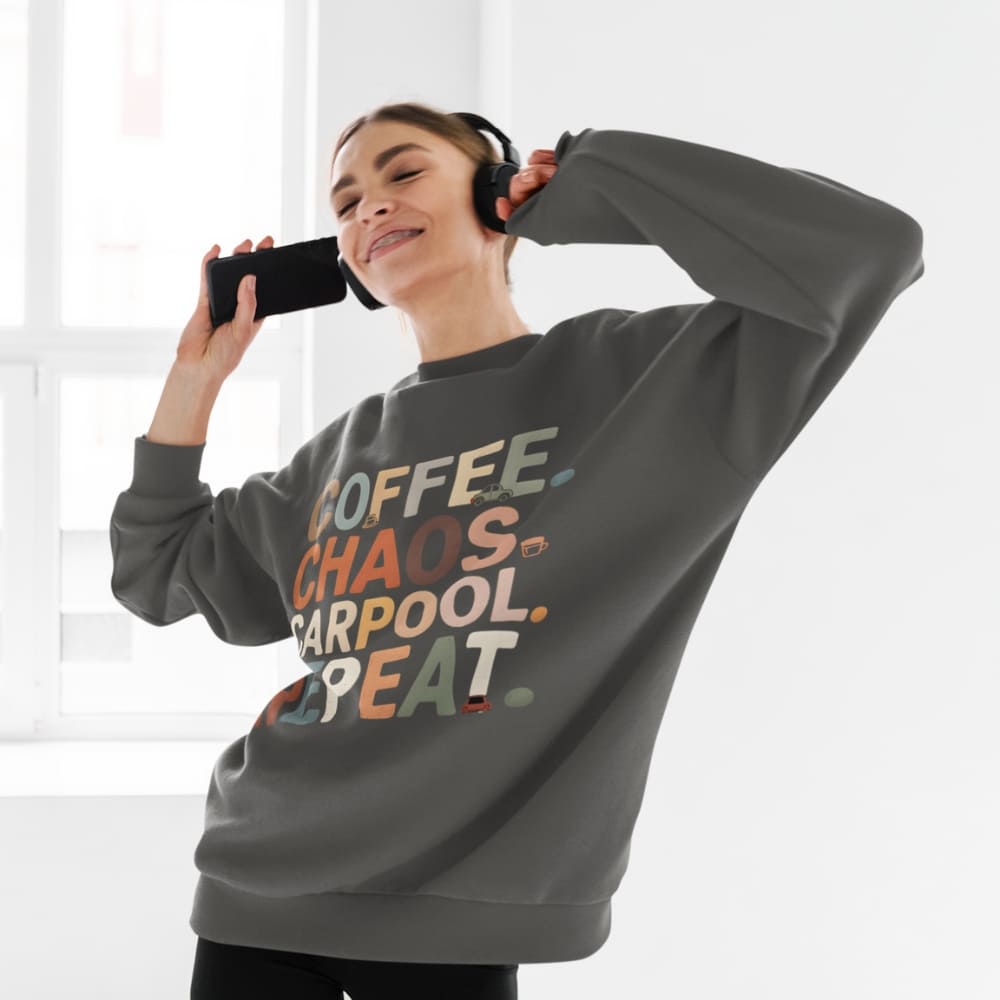 Person wearing a gray sweatshirt with colorful text, holding a phone to their ear.
