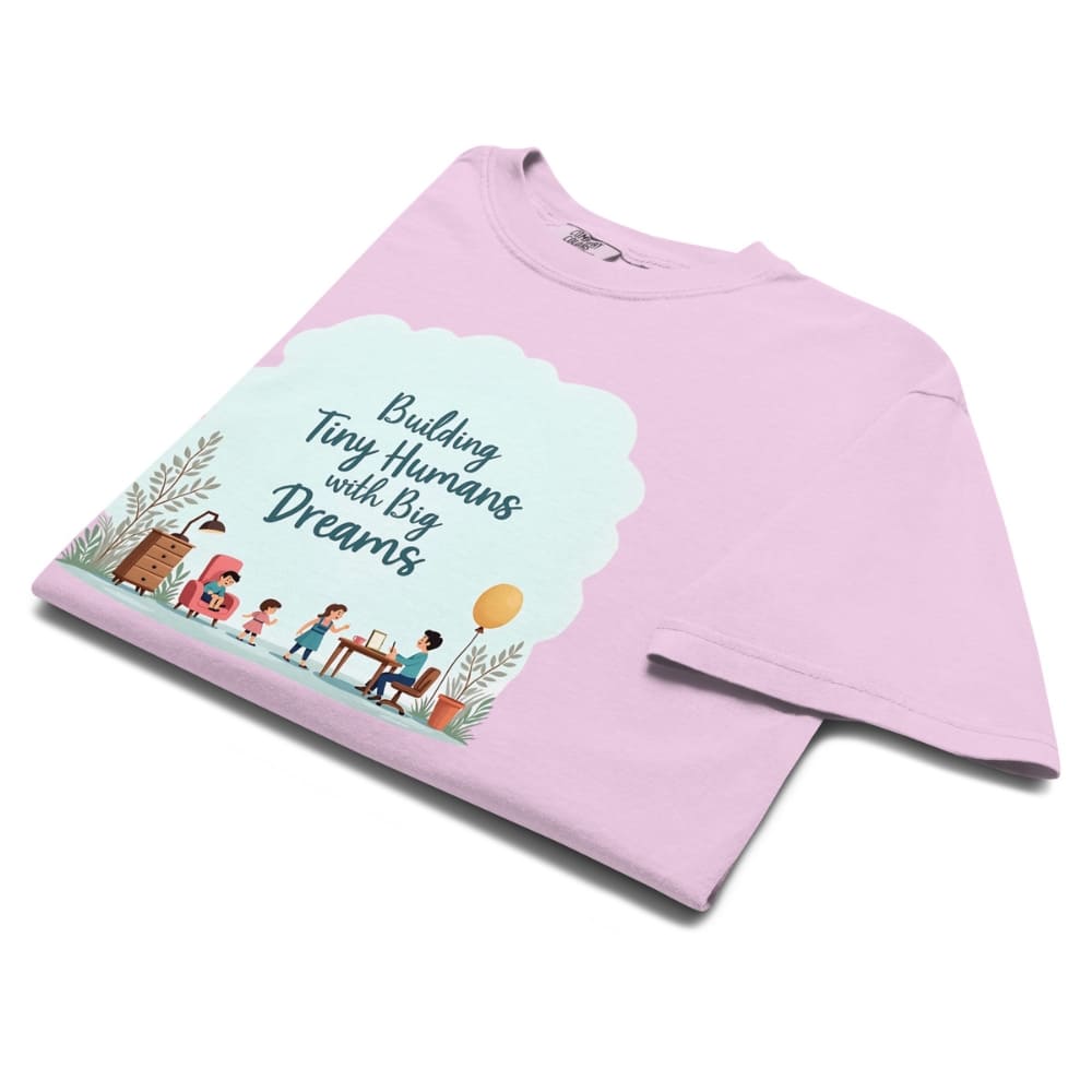 Illustrated t-shirt design with the quote "Building Tiny Humans with Big Dreams" surrounded by a family parenting scene