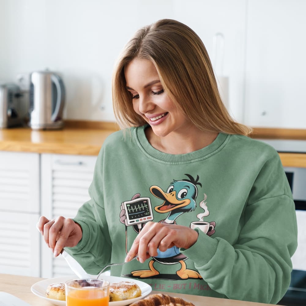 Woman wearing a green sweatshirt with a cartoon character, sitting at a kitchen table.