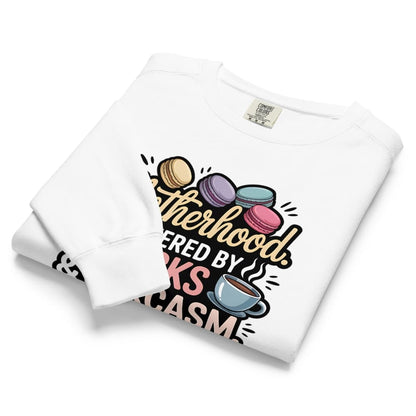 Sweatshirt design with text “Motherhood. Powered by Snacks & Sarcasm.” featuring colorful macarons and a steaming coffee cup on vintage-washed cotton fleece.