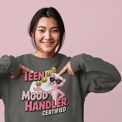 Person wearing a sweatshirt with 'TEEN MOOD HANDLER CERTIFIED' design on a pink background