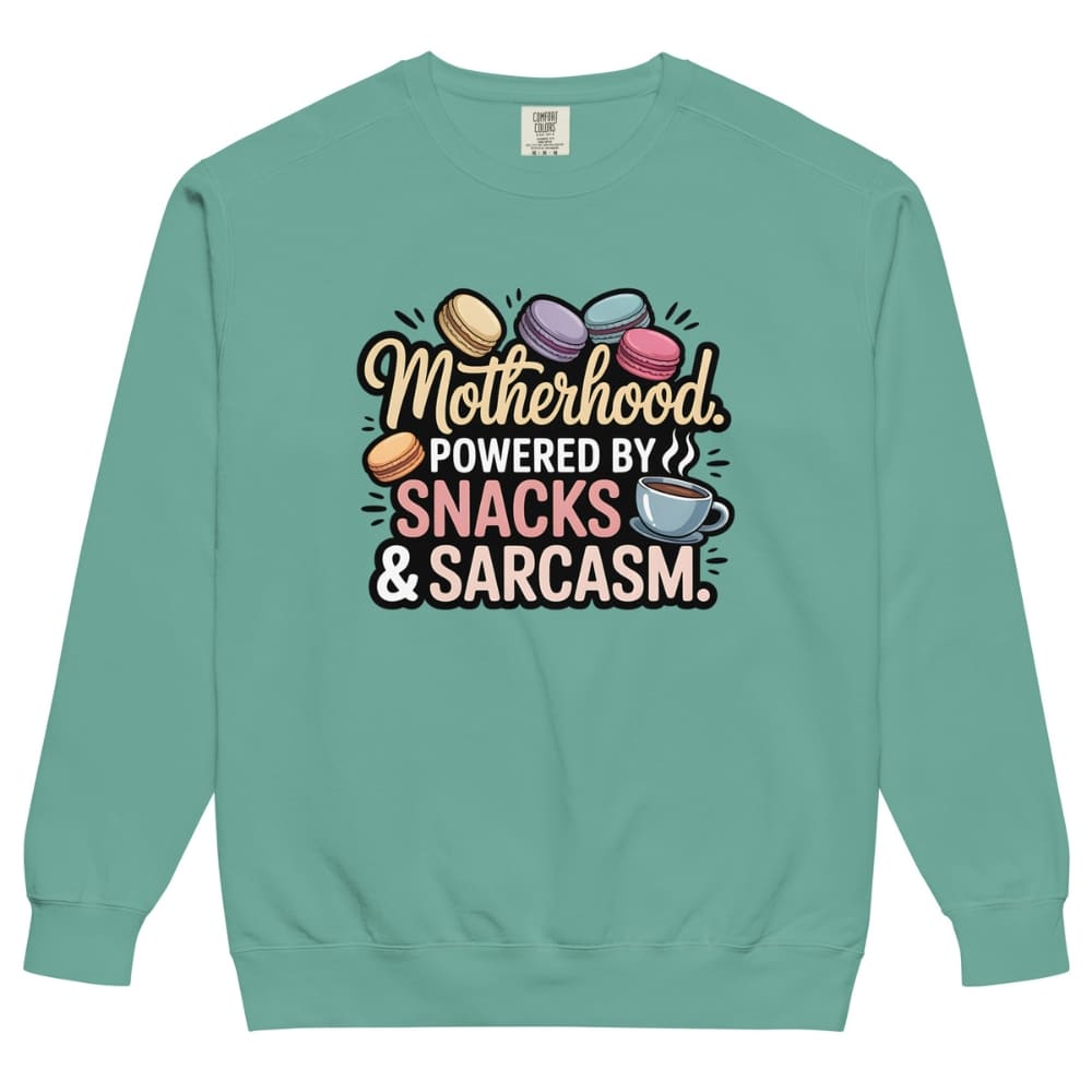 Sweatshirt design with text “Motherhood. Powered by Snacks & Sarcasm.” featuring colorful macarons and a steaming coffee cup on vintage-washed cotton fleece.